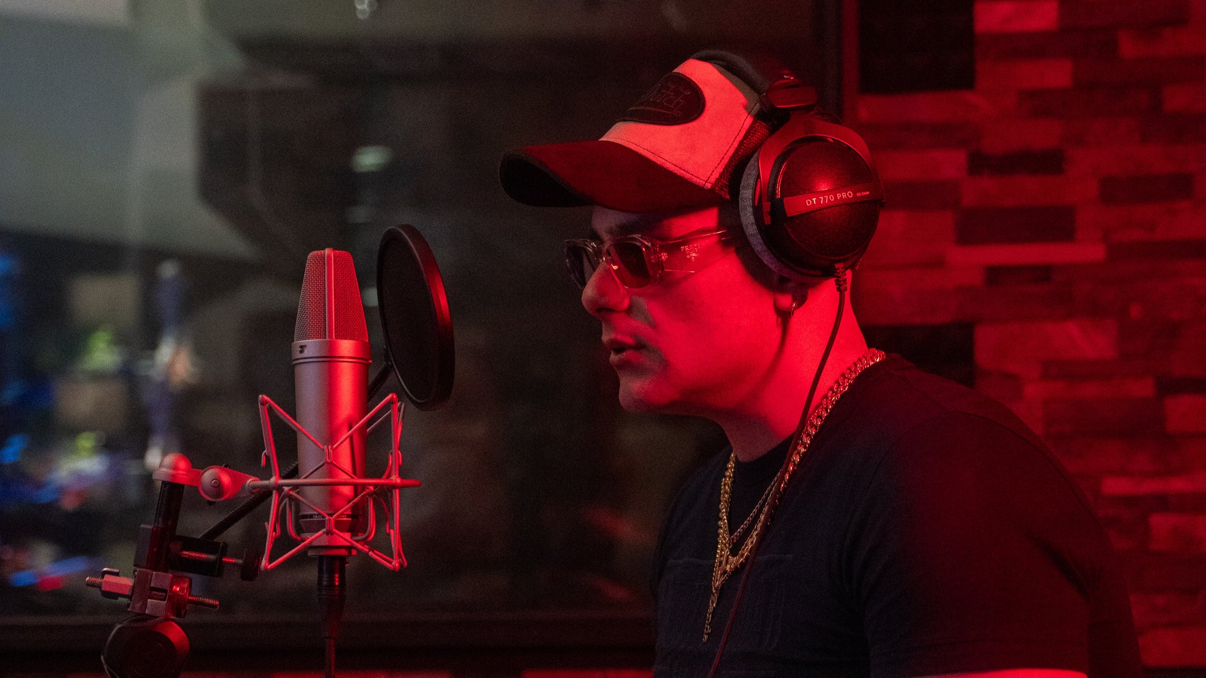 zanda in a recording studio with microphone and headphones, red lighting.